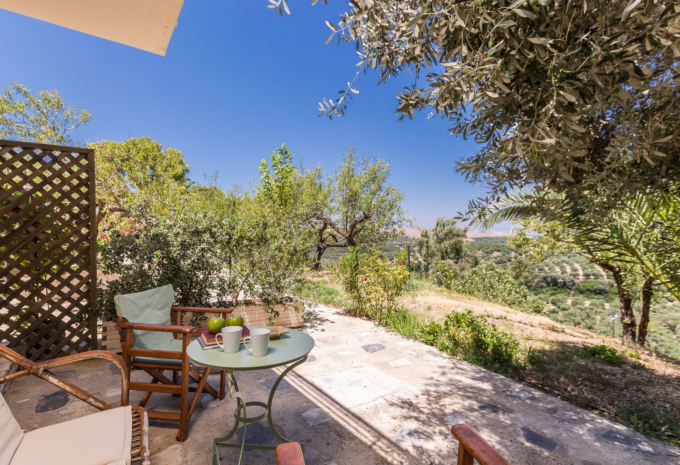 An outdoor patio with a table, chairs, and a view of the countryside.