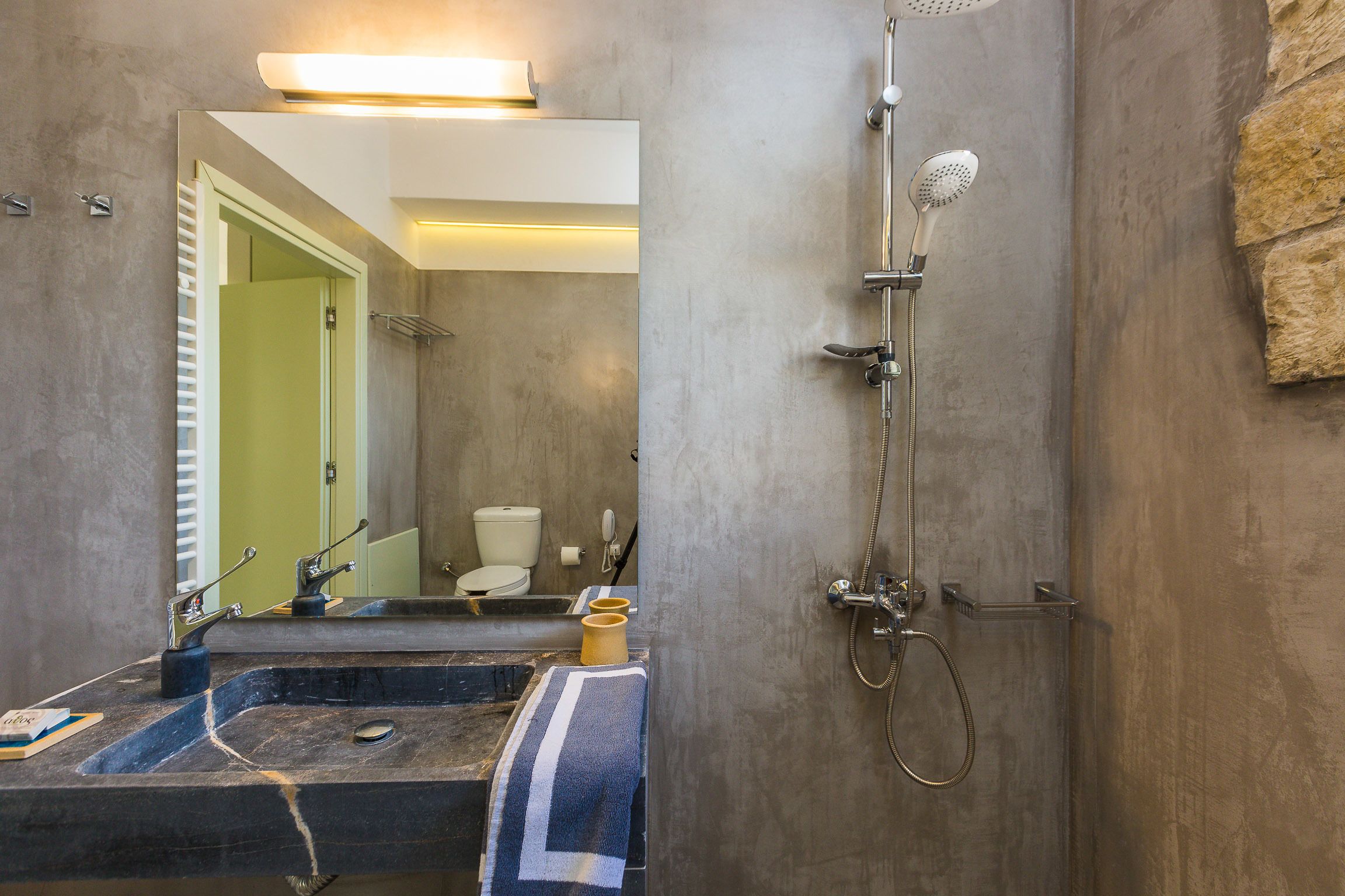 A bathroom with a large mirror, a sink, a shower, and a towel rack.