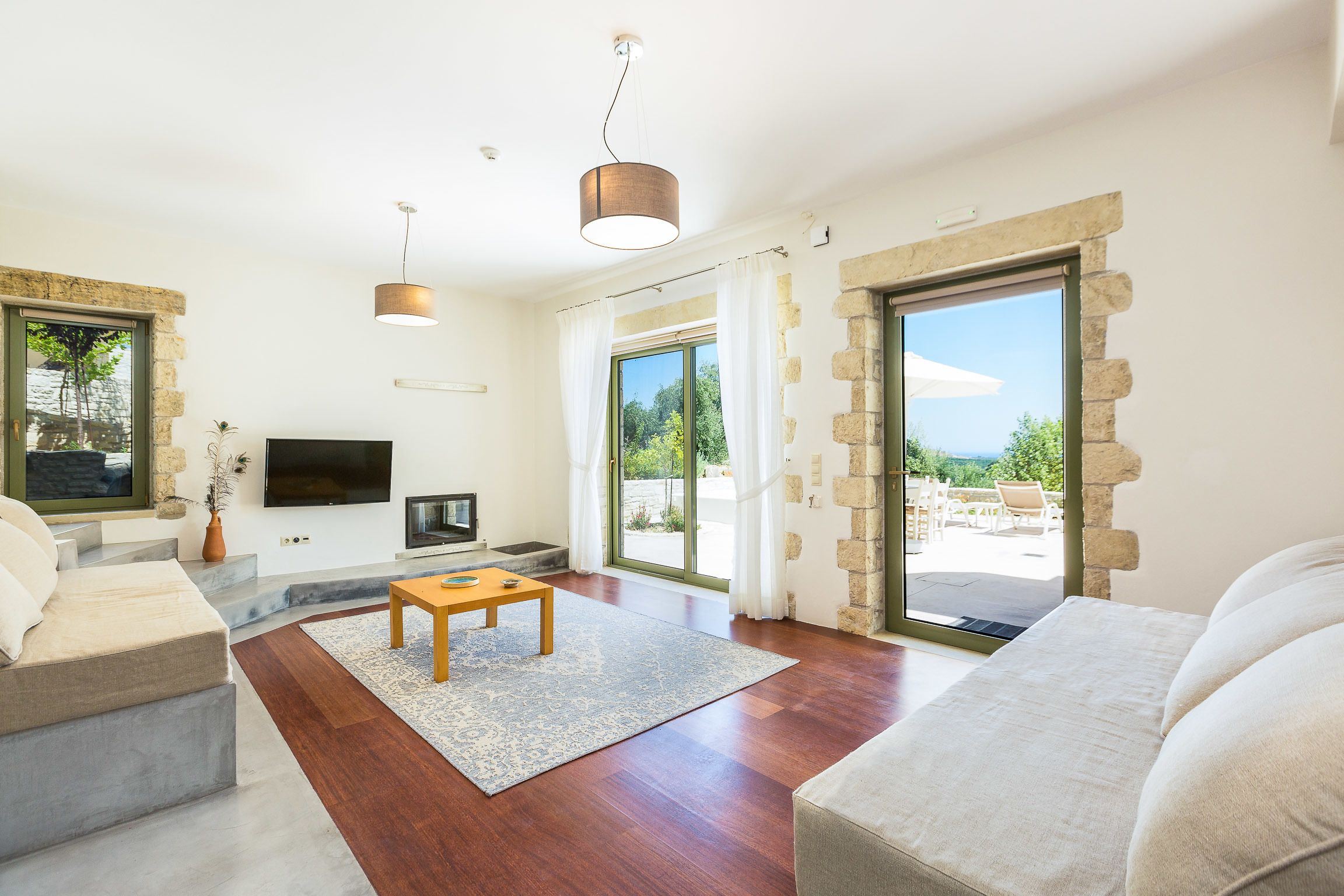 Un salón moderno con televisor de pantalla plana, una mesa de centro de madera y una pared de piedra.