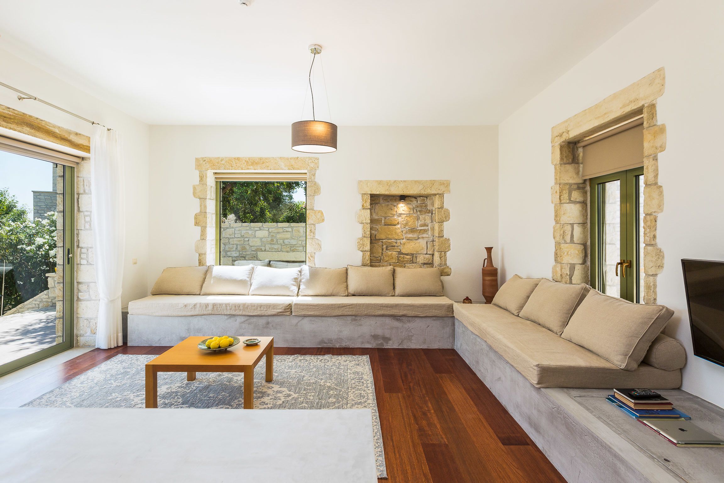 A modern living room with a stone fireplace, a sofa, a coffee table, and a TV.