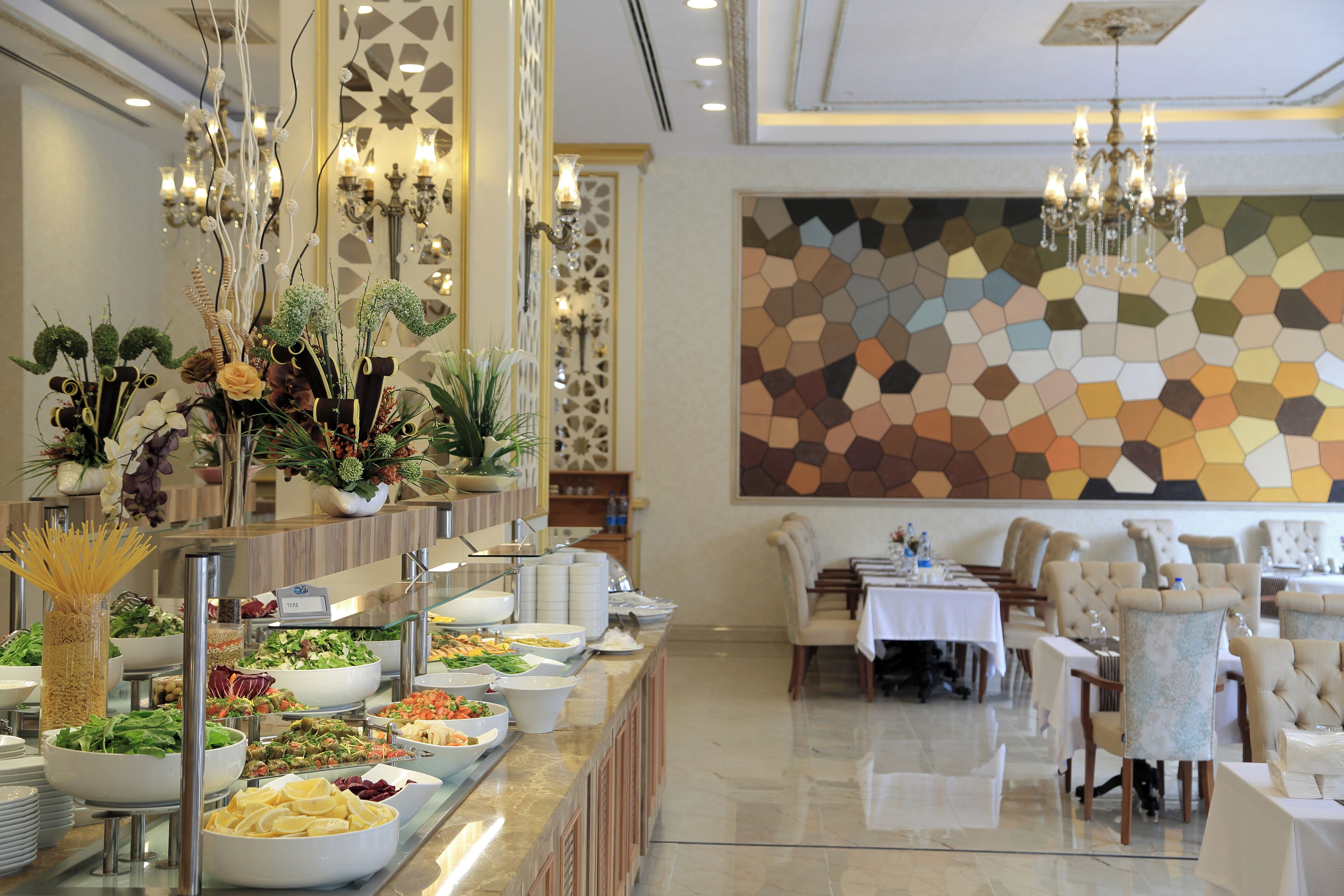 Un espace buffet proposant une variété de plats, un coin repas avec des tables et des chaises, et des luminaires décoratifs.