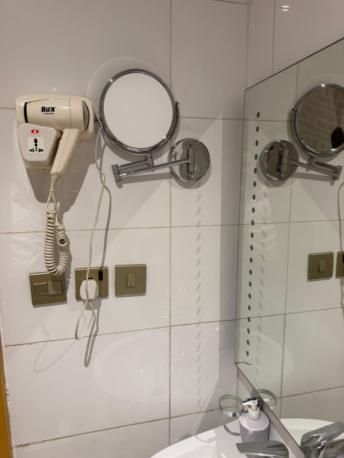 Ein Badezimmer mit Fön, Spiegel und Waschbecken.