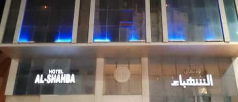 A hotel with a modern facade, large glass windows, and illuminated blue accents.