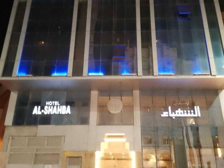 Hotel amb façana moderna, grans finestres de vidre i detalls blaus il·luminats.
