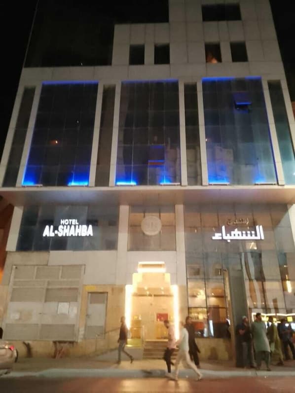 A hotel with a modern facade, large glass windows, and illuminated blue accents.