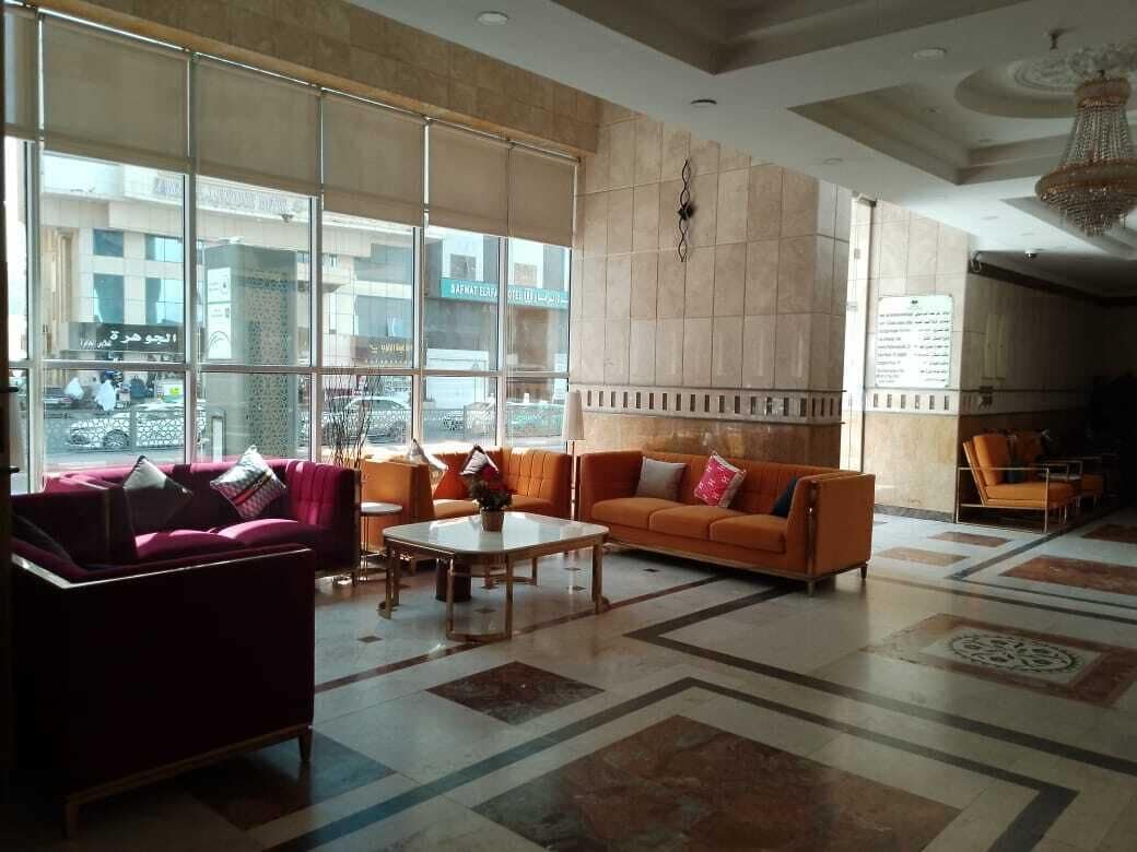 A spacious lobby with a red sofa, an orange sofa, and a coffee table. Large windows provide a view of the street outside.