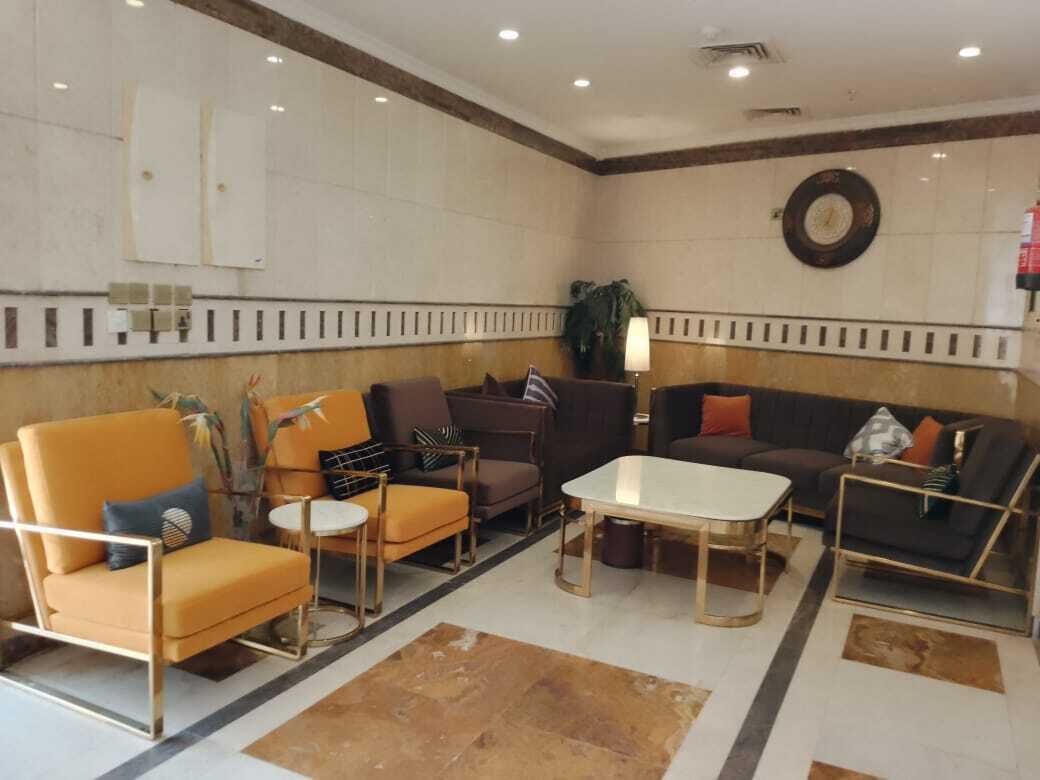 Een hal met een bank, fauteuils, een salontafel en een lamp.