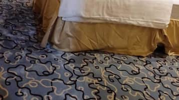 Habitació d'hotel amb dos llits, una catifes amb dibuixos i un panell de fusta al capçal.