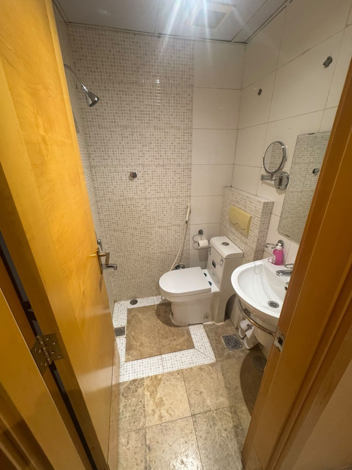 A bathroom with a shower, toilet, sink, and mirror.