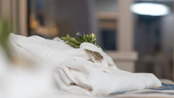Una toalla blanca doblada con una pequeña planta verde sobre la cama.
