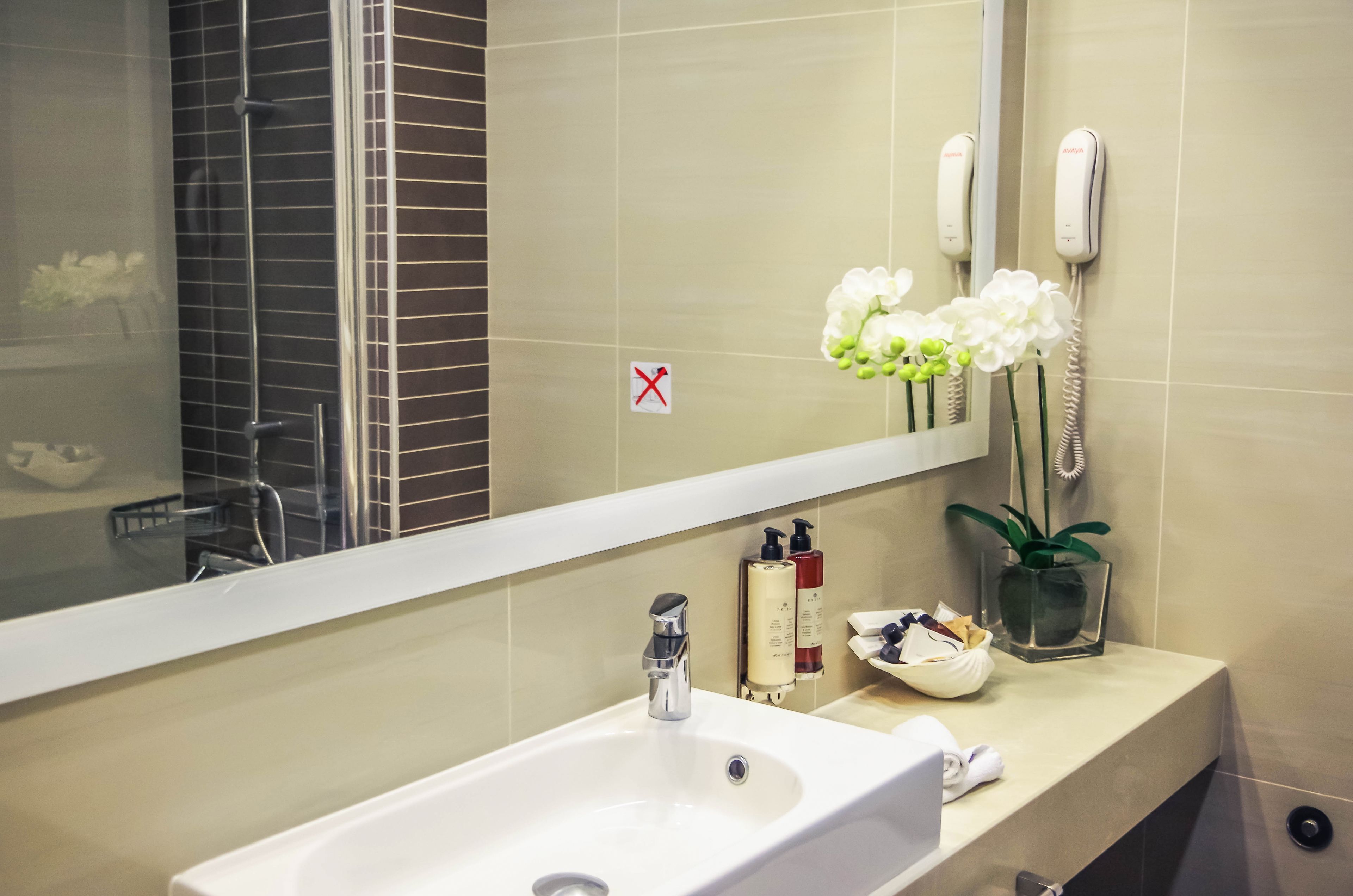 Ein Badezimmer mit Waschbecken, Spiegel und Pflegeprodukten.