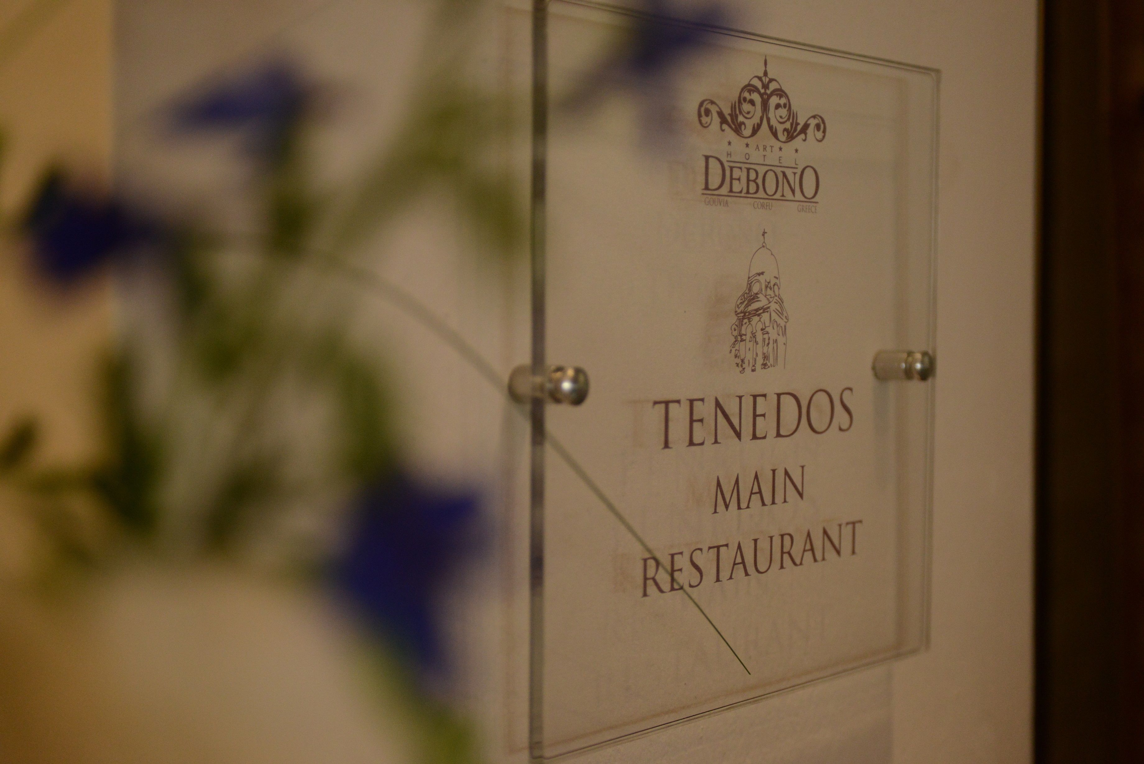 Une enseigne indiquant « TENEDOS MAIN RESTAURANT », avec un emblème décoratif au-dessus du nom.