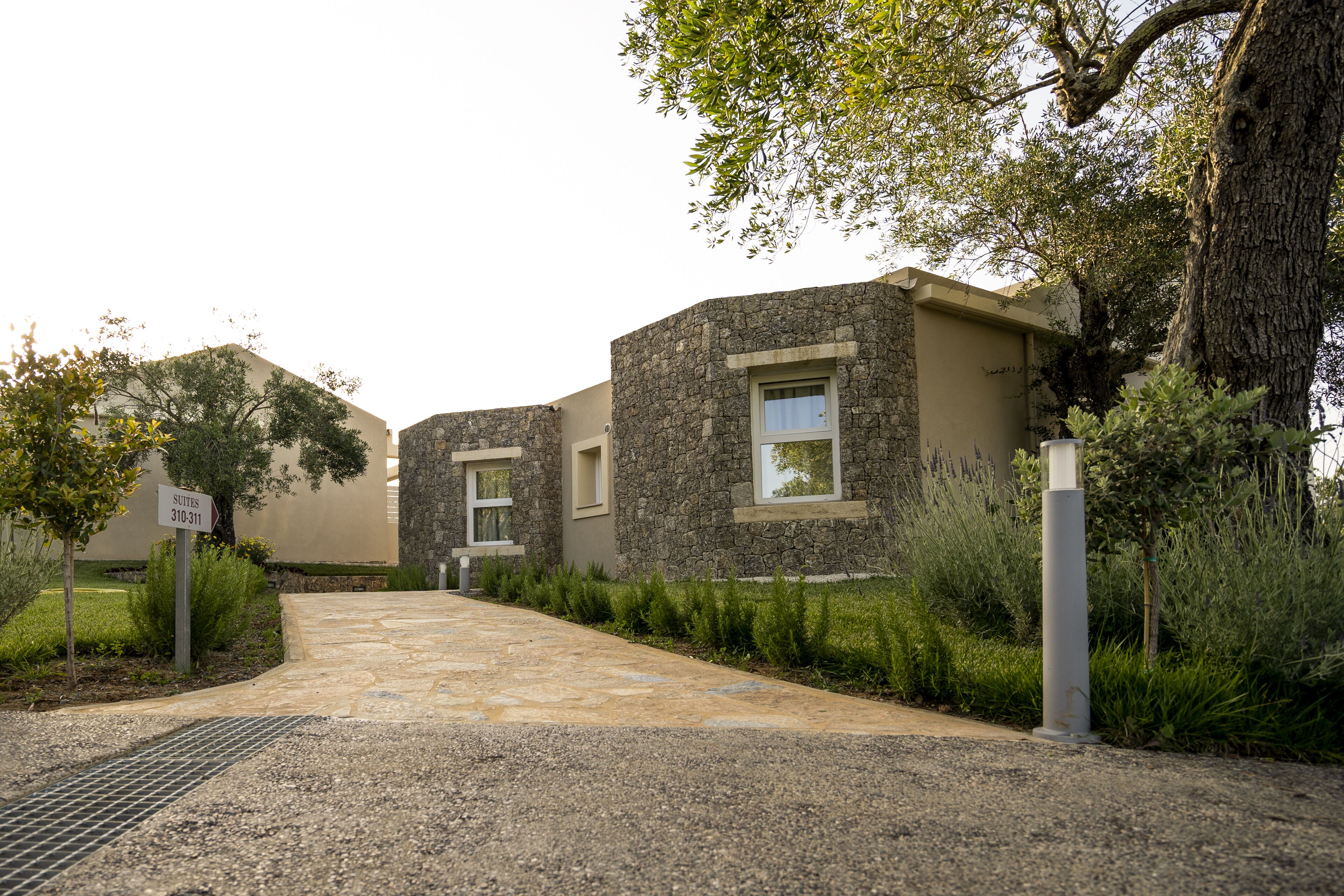 Un edificio con facciata in pietra, ingresso lastricato e un cartello che indica 'Suites 310-311'.