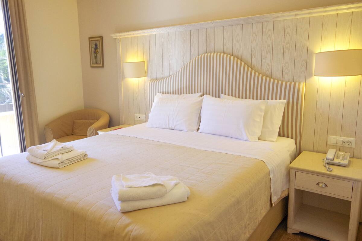 A neatly made bed with white linens, a bedside lamp, and a telephone on the nightstand.