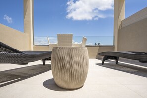 A rooftop terrace with wicker lounge chairs and a large textured planter. - Art Hotel Debono (Corfu)