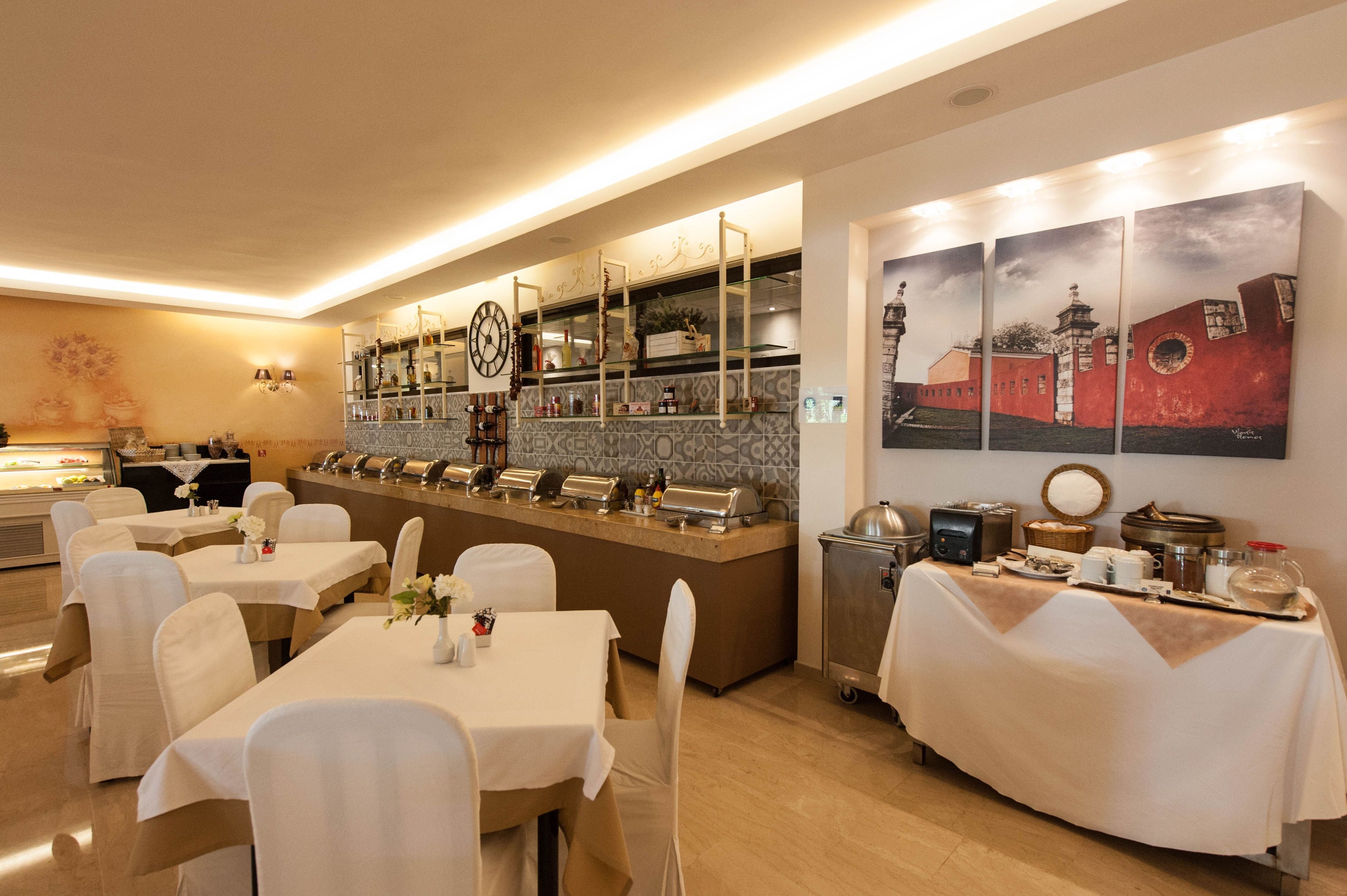 Un comedor de hotel con varias mesas, una barra de buffet y una pared decorada con obras de arte.