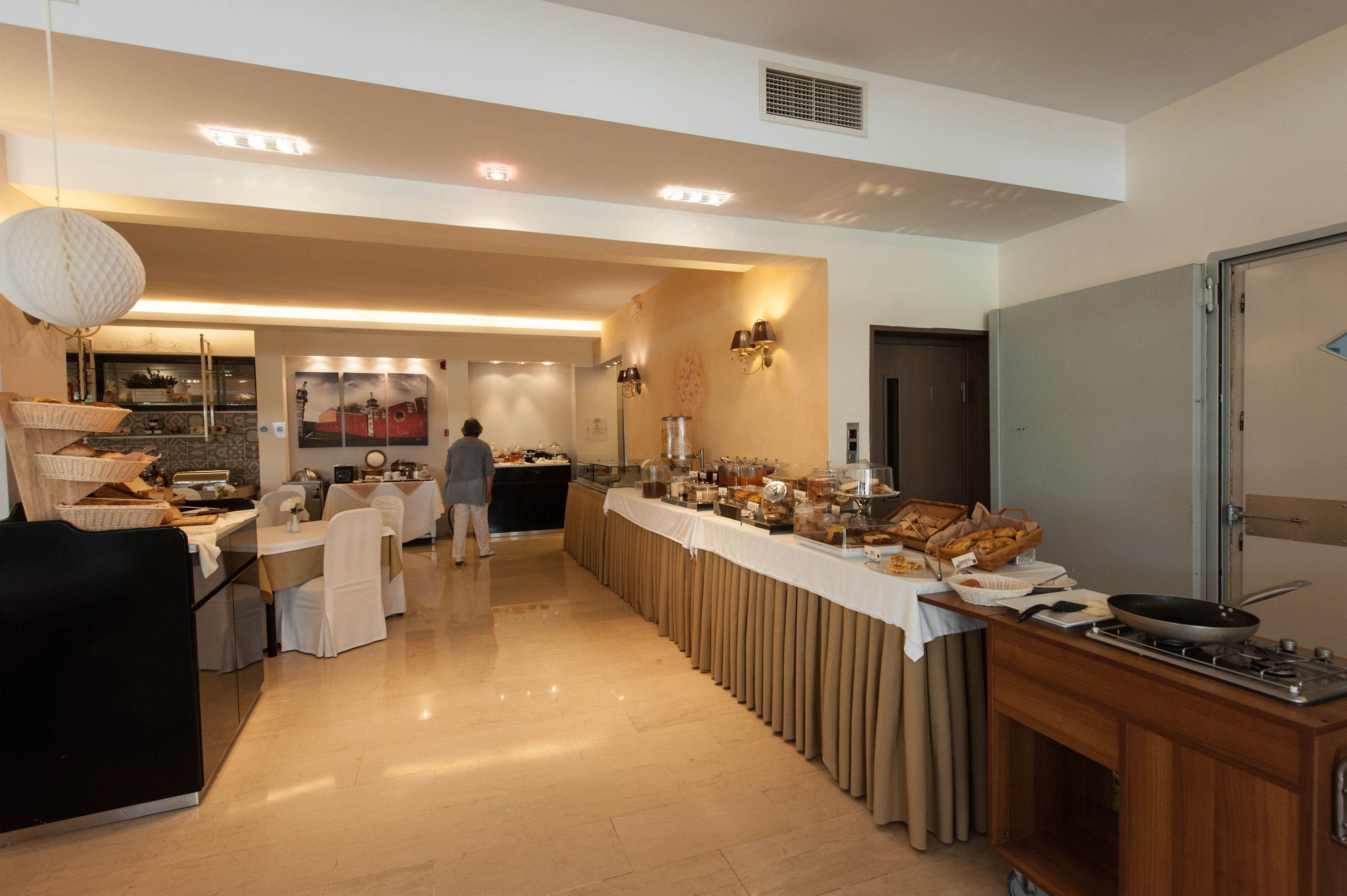 Un buffet proposant une variété de plats, une personne qui sert les clients et un espace cuisine équipé d’une cuisinière.