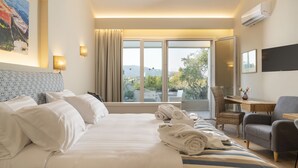 Habitación de hotel con una cama grande, un escritorio, una silla y vistas al exterior.