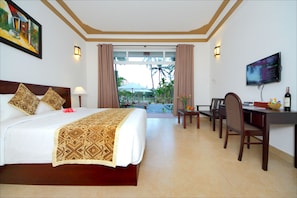 Quarto de hotel com cama, escrivaninha e televisão.