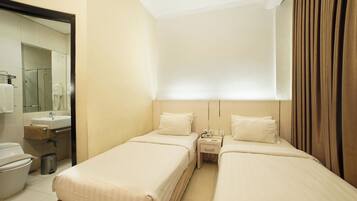 A hotel room with two beds, a bathroom, and a mirror.