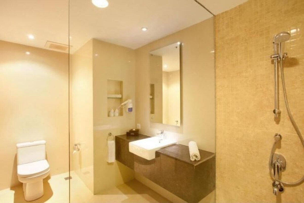 Een moderne badkamer met een douchecabine van glas, een witte wastafel en een grote spiegel.
