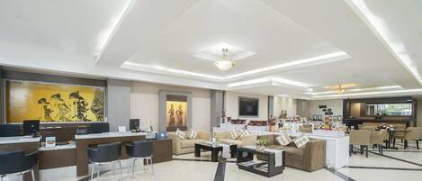 Un'accogliente hall d'hotel moderna, con reception, area salotto e spazio ristoro.