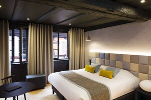 Una habitación de hotel moderna con una cama grande, una mesita de noche, una silla y una pequeña mesa.