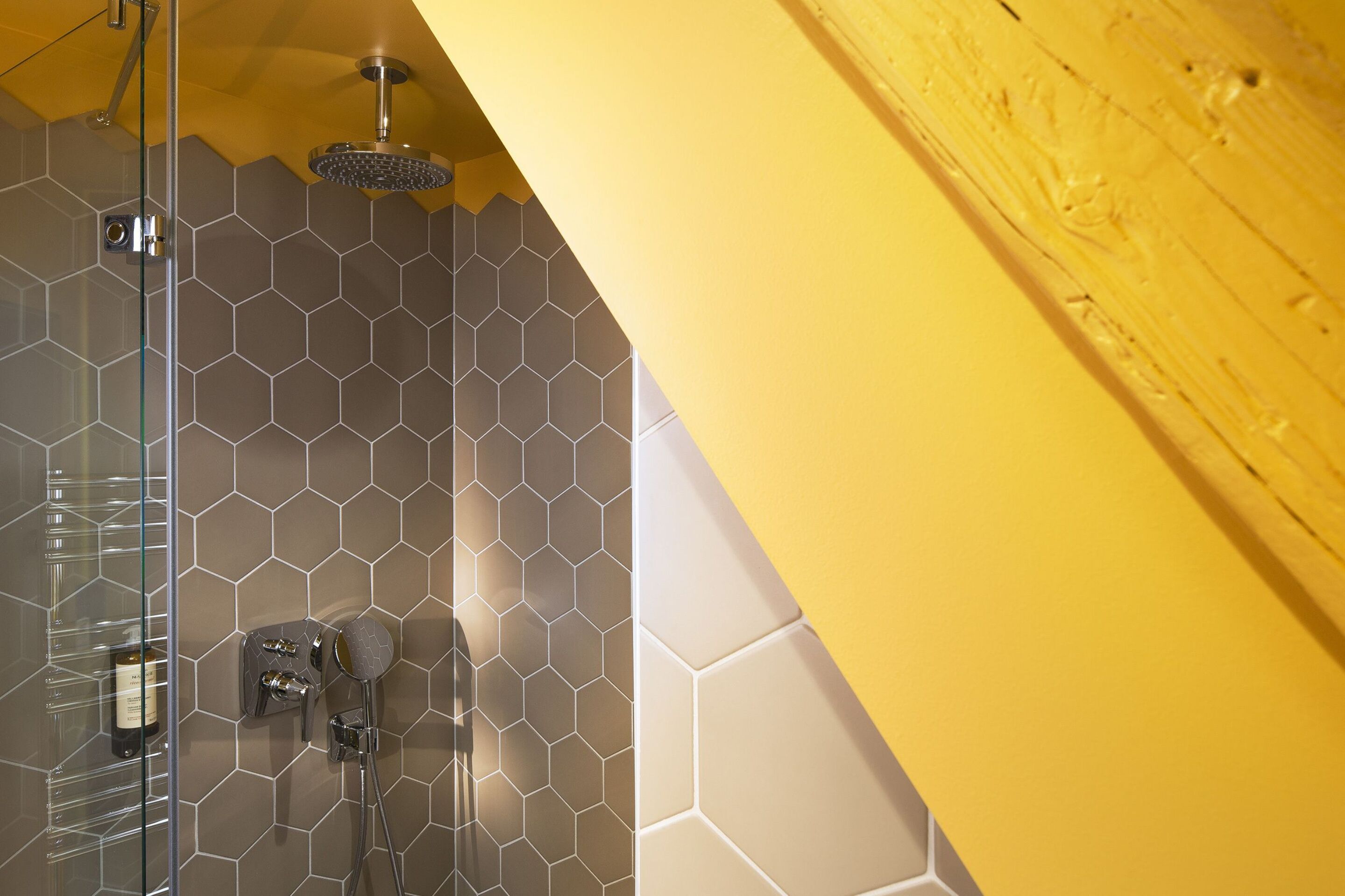 A shower with a glass door, a rain showerhead, and a handheld showerhead.