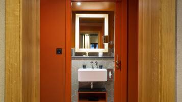 Un baño con un lavamanos blanco, un espejo y una puerta de madera.