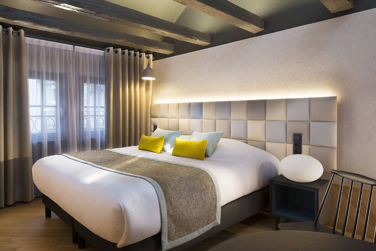 Ein modernes Schlafzimmer mit einem großen Bett, Nachttischen und einem Kopfteil mit integrierter Beleuchtung.