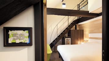 A bedroom with a bed, a framed number sign, a staircase, and a small window.