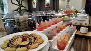 Un buffet proposant une variété de plats et de boissons, notamment une assiette de gaufres avec du sirop et un assortiment de boissons colorées.