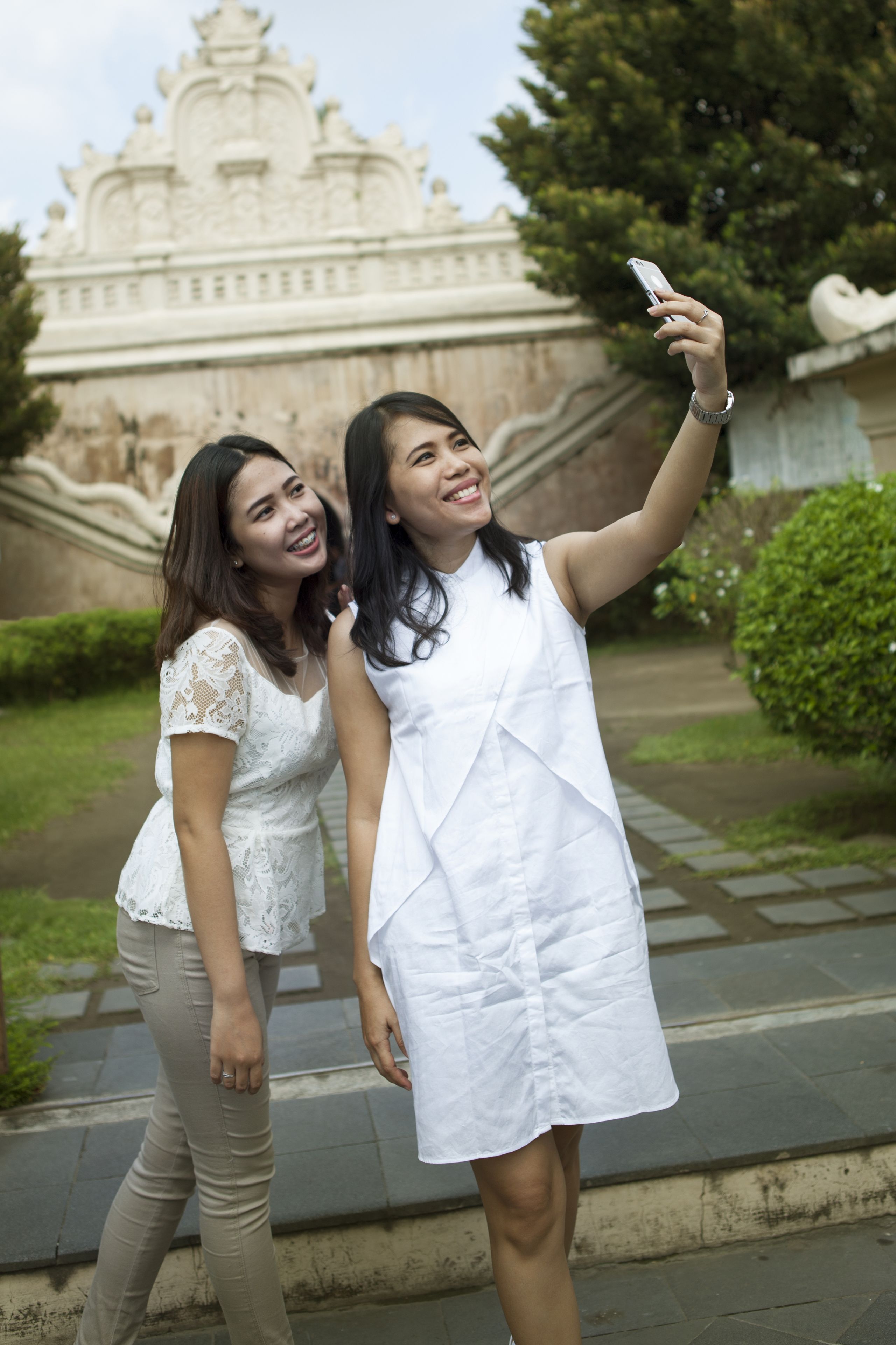 Two individuals taking a selfie in front of a historic building with intricate architecture.