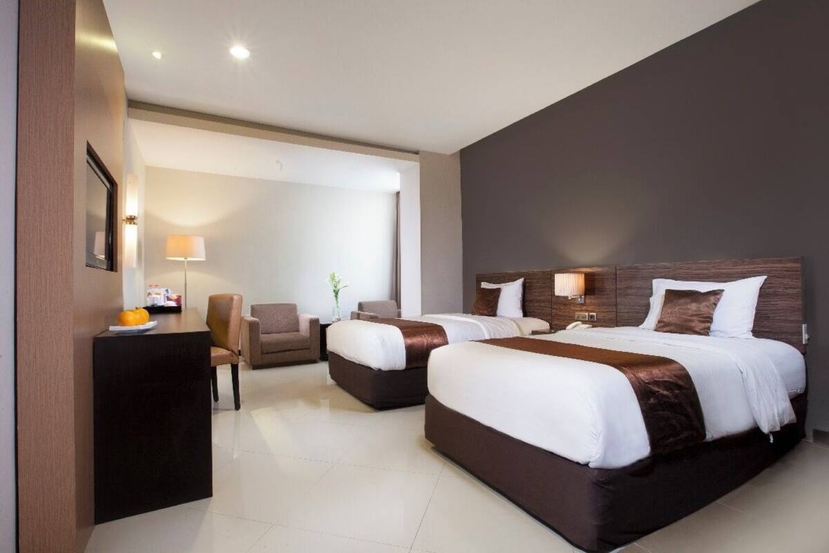 Een moderne hotelkamer met twee bedden, een bureau en een stoel.