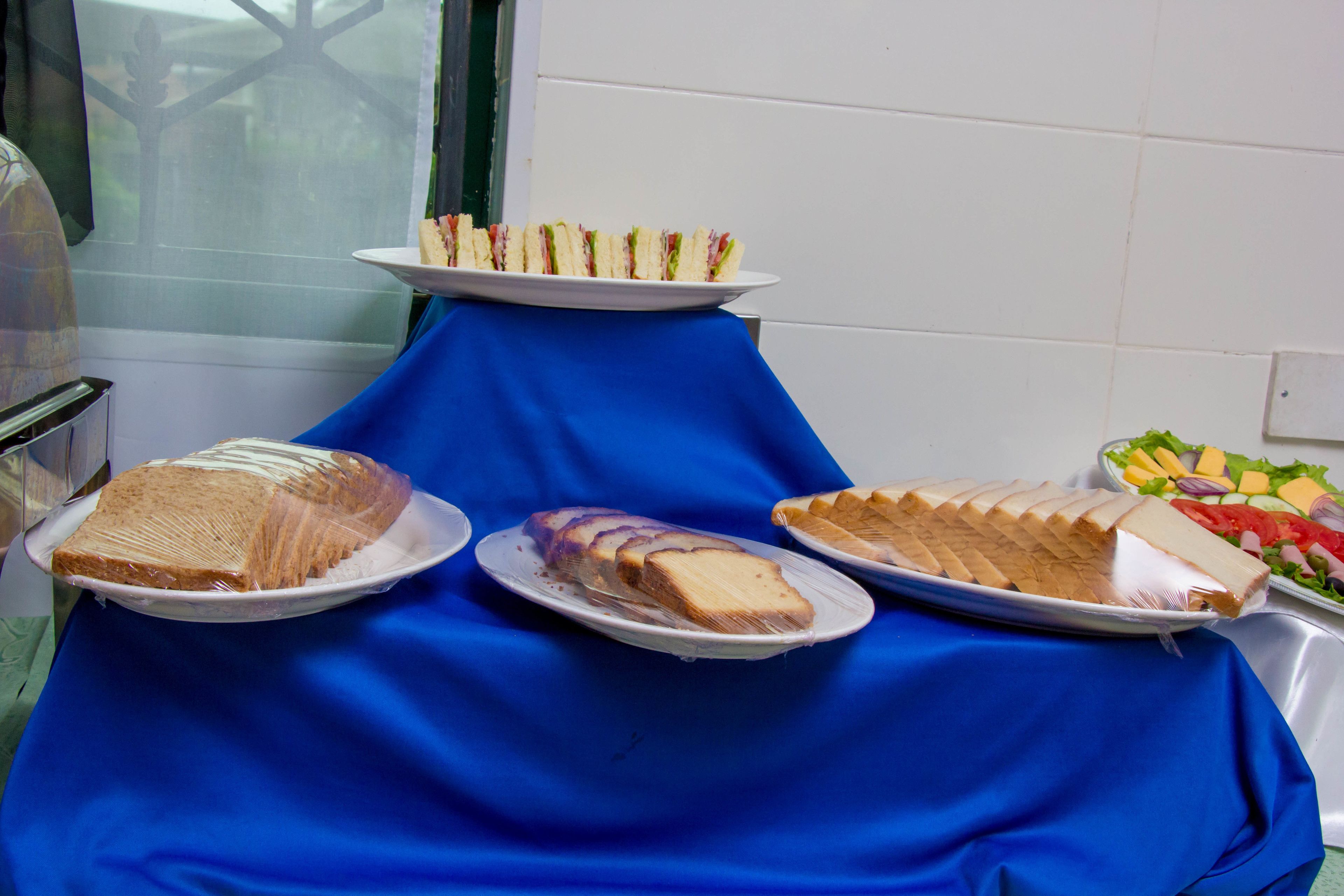 Ein Buffet mit verschiedenen Speisen, darunter Sandwiches, Kuchen und Salat.