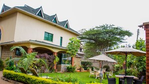 Une maison à deux étages dotée d’un patio aménagé avec du mobilier d’extérieur et un jardin.