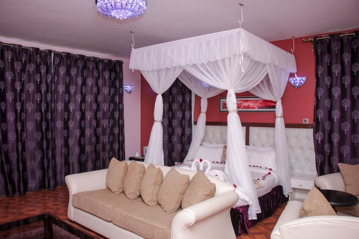 A room with a white canopy bed, a white sofa, and a small table.