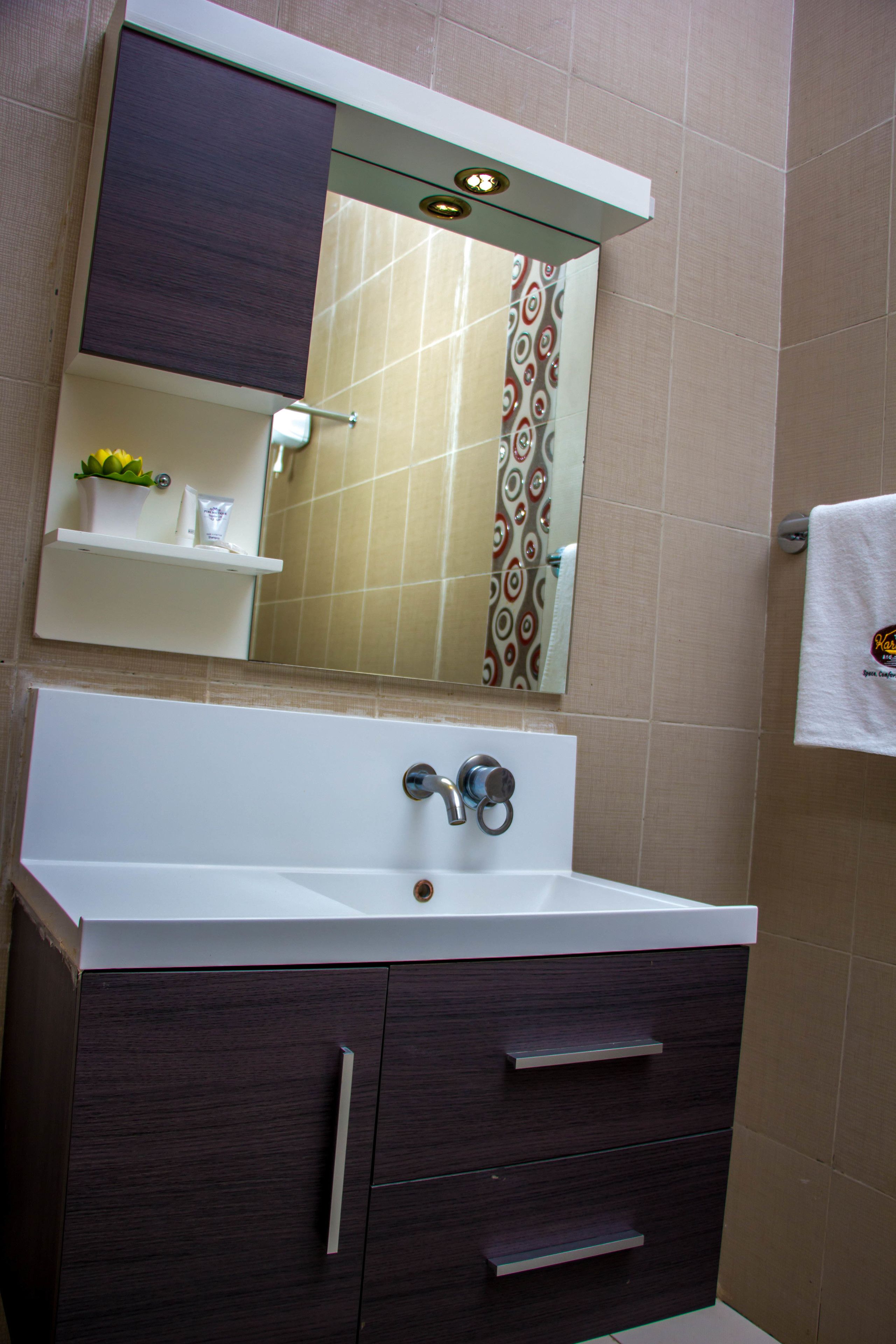 A bathroom with a white sink, dark wood cabinet, and a mirror above it.