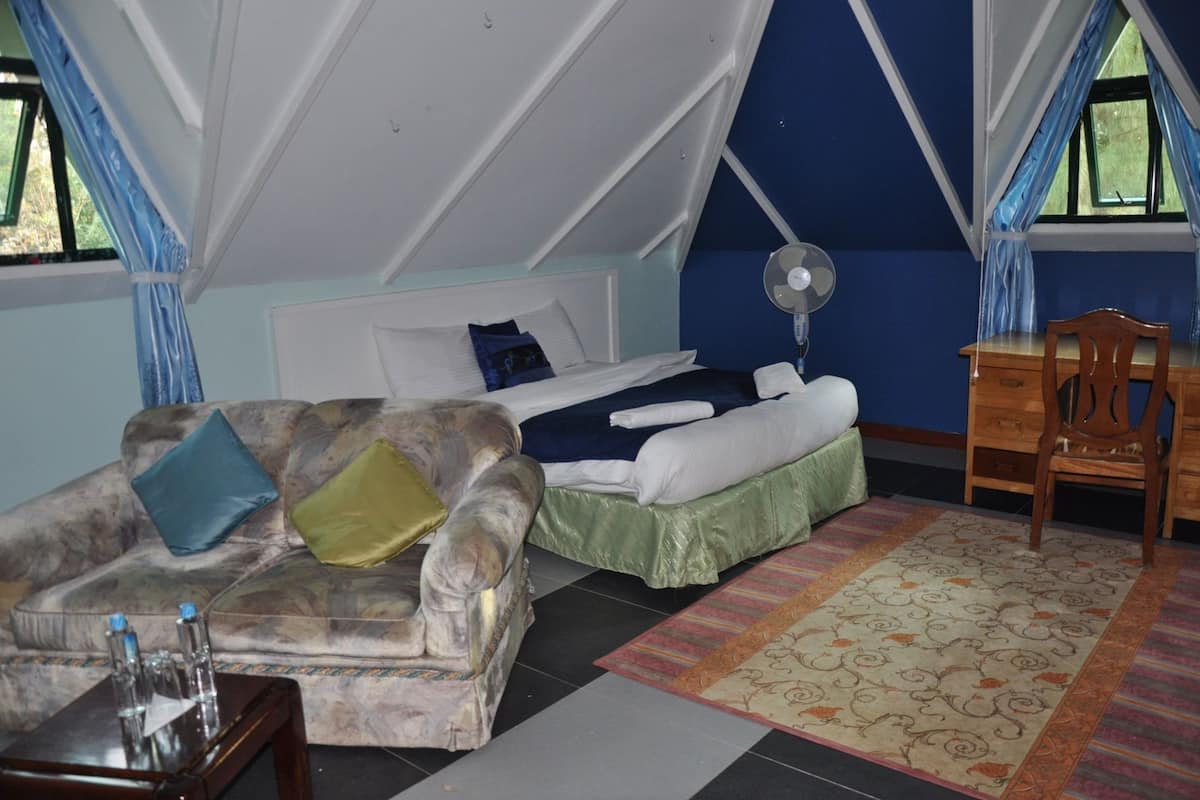 A tent-style room with a bed, a sofa, a desk, and a fan.