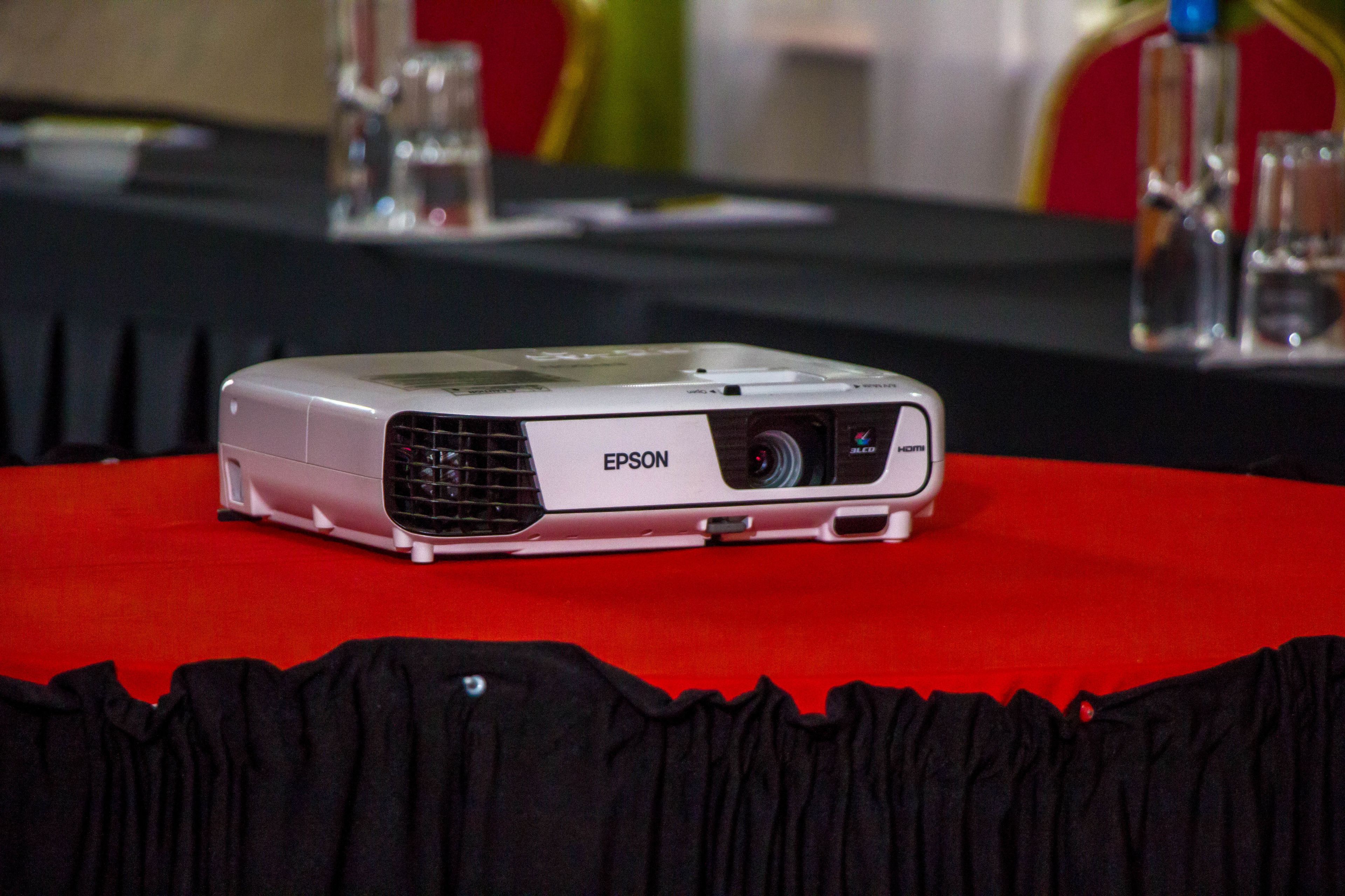 A projector on a table with a red tablecloth.