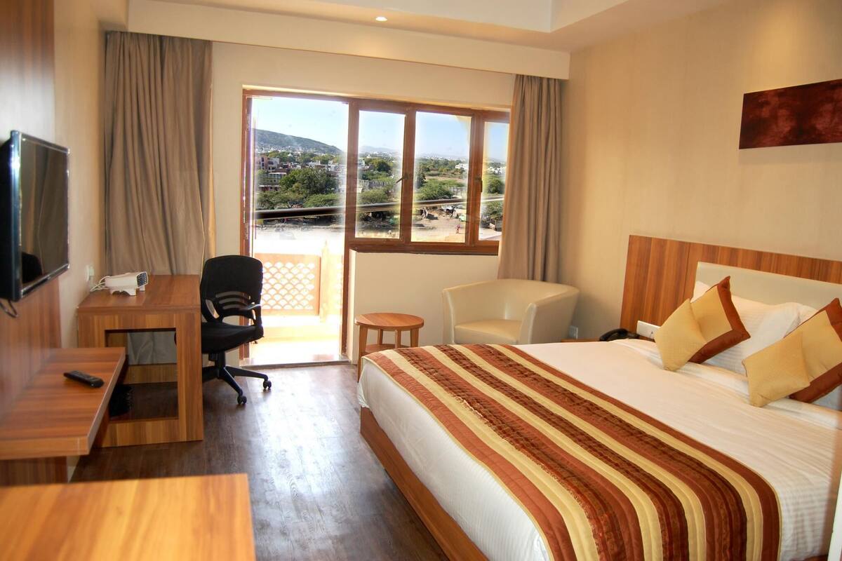 Una habitación de hotel con cama, escritorio, silla y televisor.
