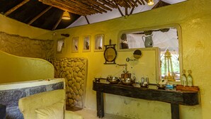 A rustic bathroom with a stone wall, wooden bench, and a wooden sink with various toiletries. - Mbweha Camp Lake Nakuru (Nakuru)