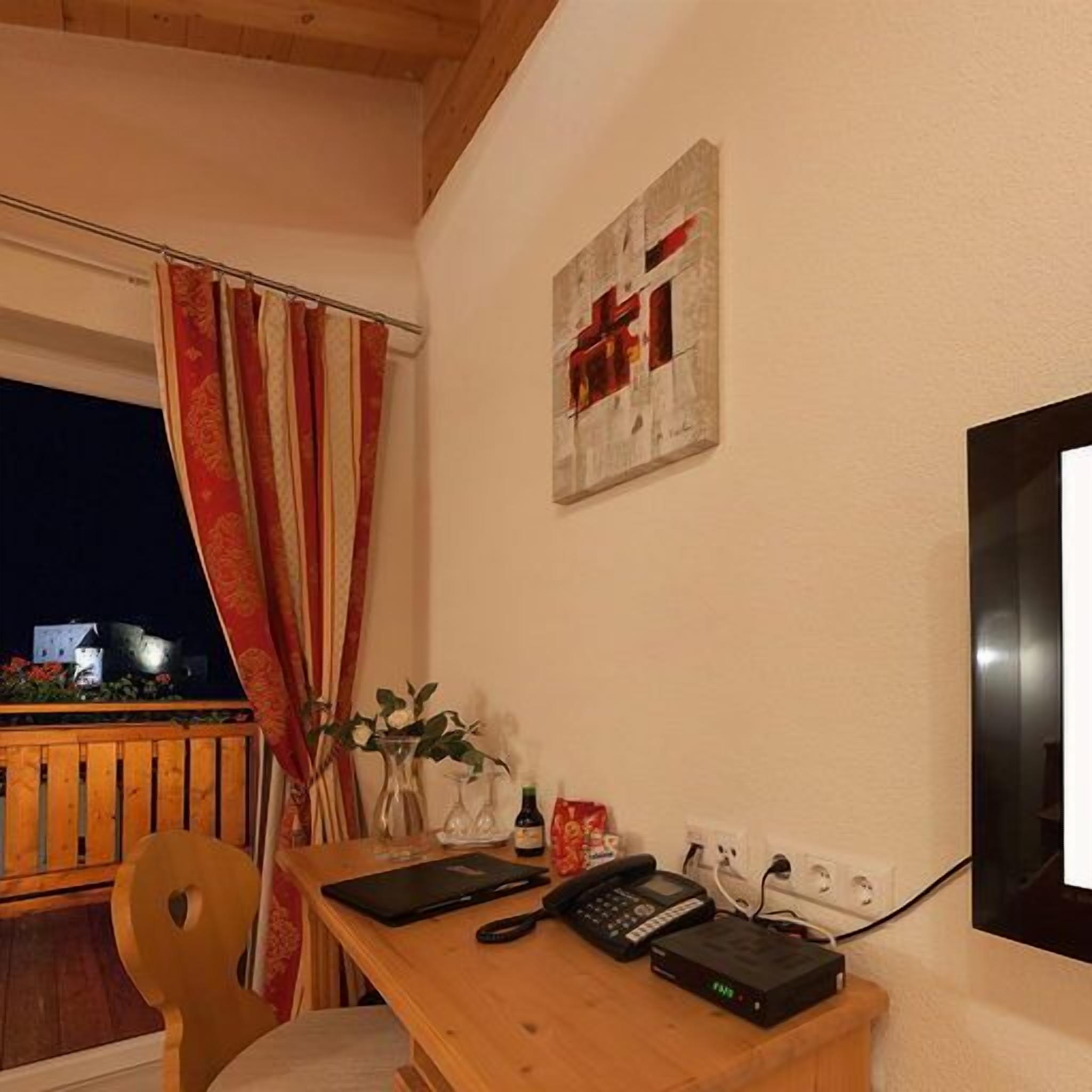 A room with a wooden desk, a telephone, a router, and a painting on the wall.