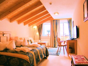 A hotel room with a bed, a desk, a chair, a television, and a window with curtains. - Hotel Berghof (Nauders)