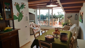 A cozy kitchen with a dining table set for four, a wooden ceiling, and a view of the outdoor patio. - PalermiT'amo (Palermo)