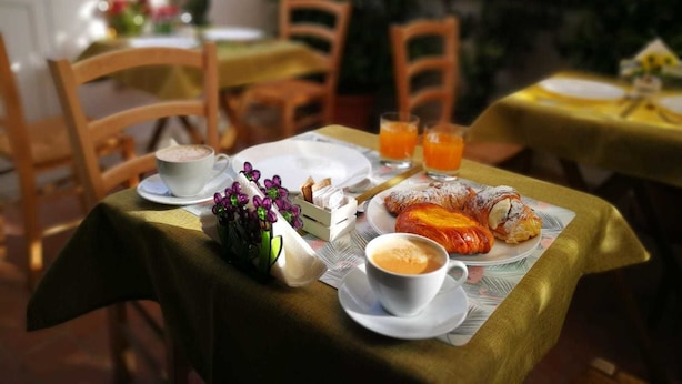 A breakfast setting with a table set for two, including croissants, orange juice, and coffee. - PalermiT'amo (Palermo)