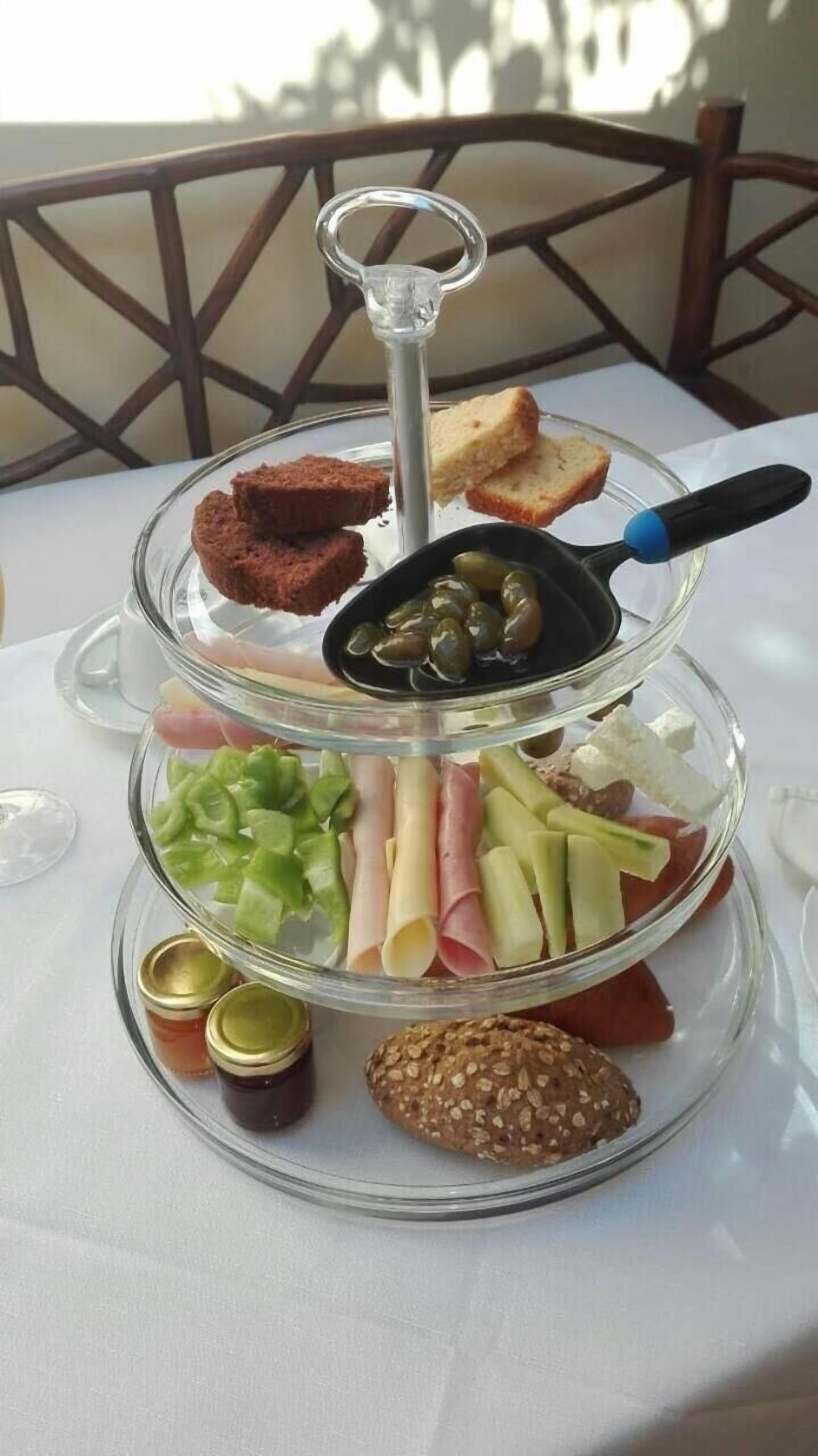 Un expositor de vidrio de tres niveles con diversos aperitivos y condimentos.
