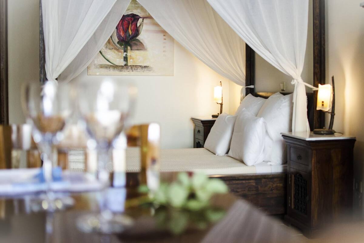 Una habitación de hotel con cama, mesita de noche y un cuadro en la pared.