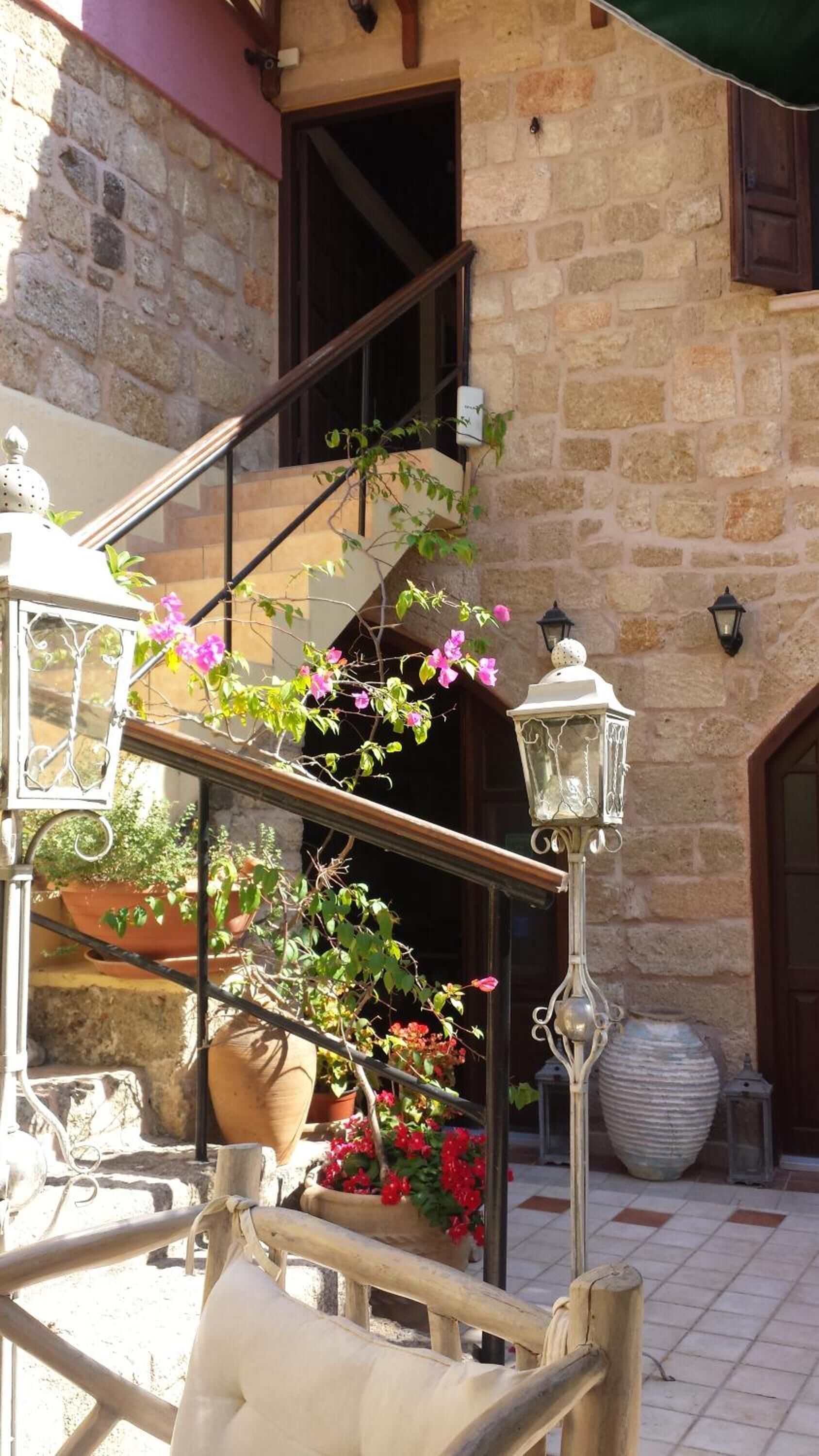 A stone building with a staircase, outdoor seating, and potted plants.