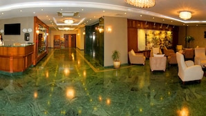 Een hotel lobby met een receptiebalie, een zithoek en een bar.